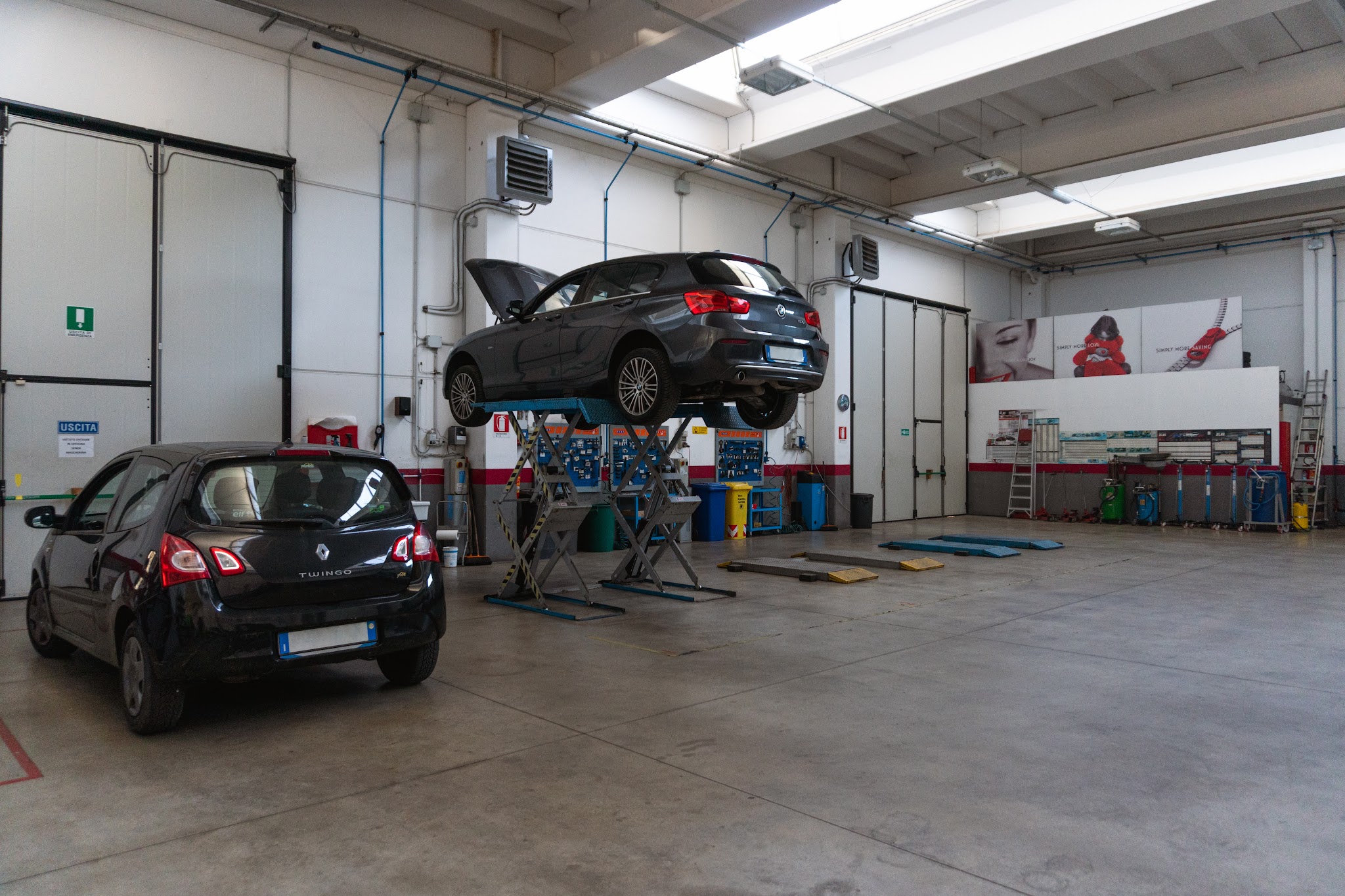 Interno dell'officina La Fiorini con un'auto sul ponte